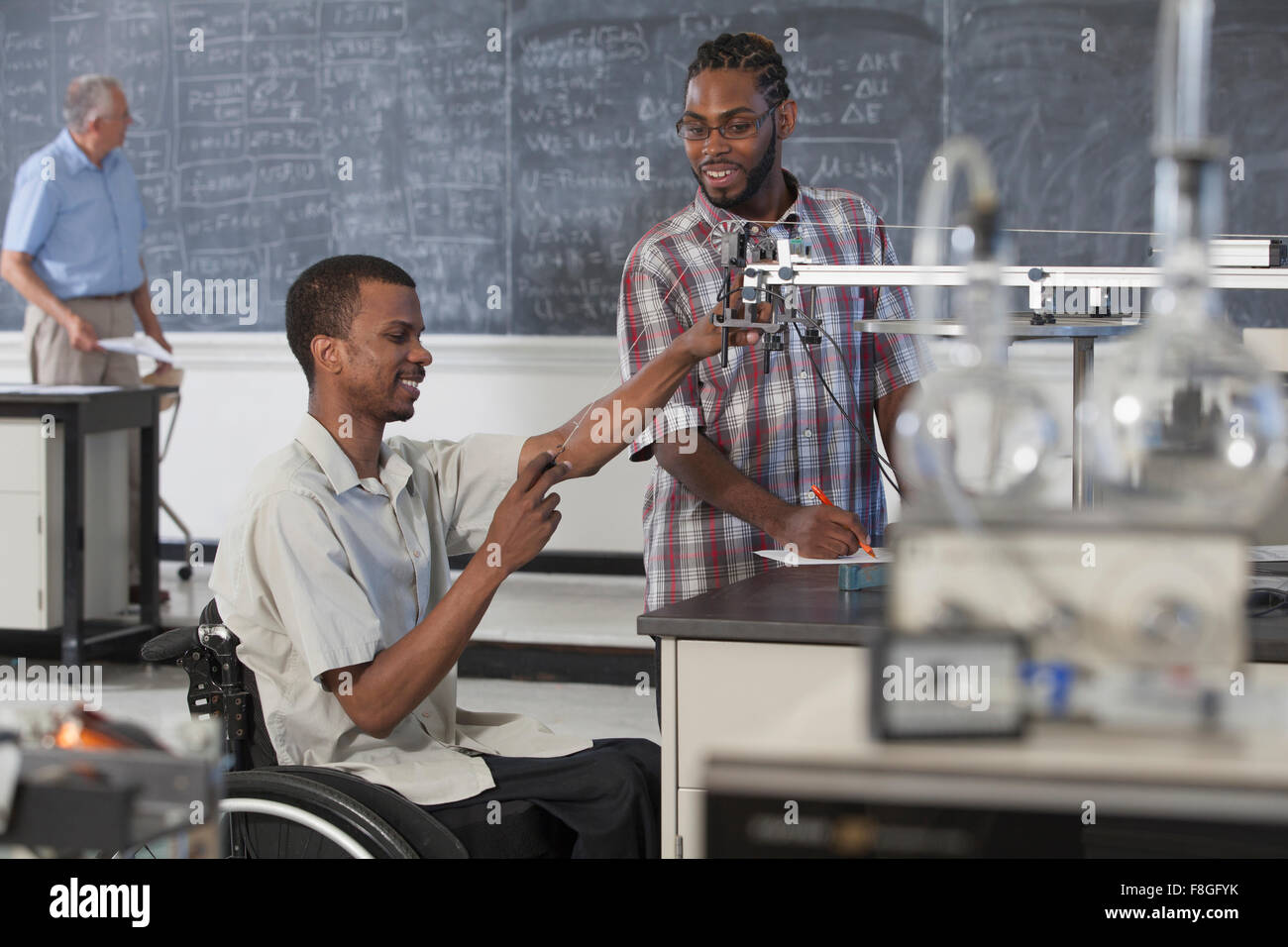 Per paraplegici studente lavora con un compagno di classe nella classe di scienze Foto Stock