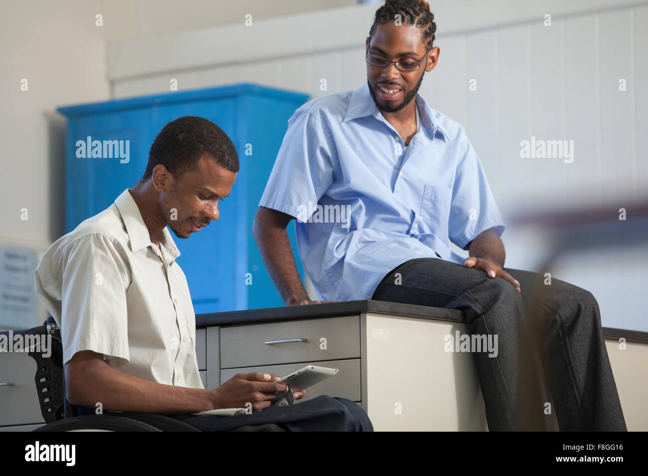 Studente di paraplegici e compagno di classe utilizzando tavoletta digitale Foto Stock