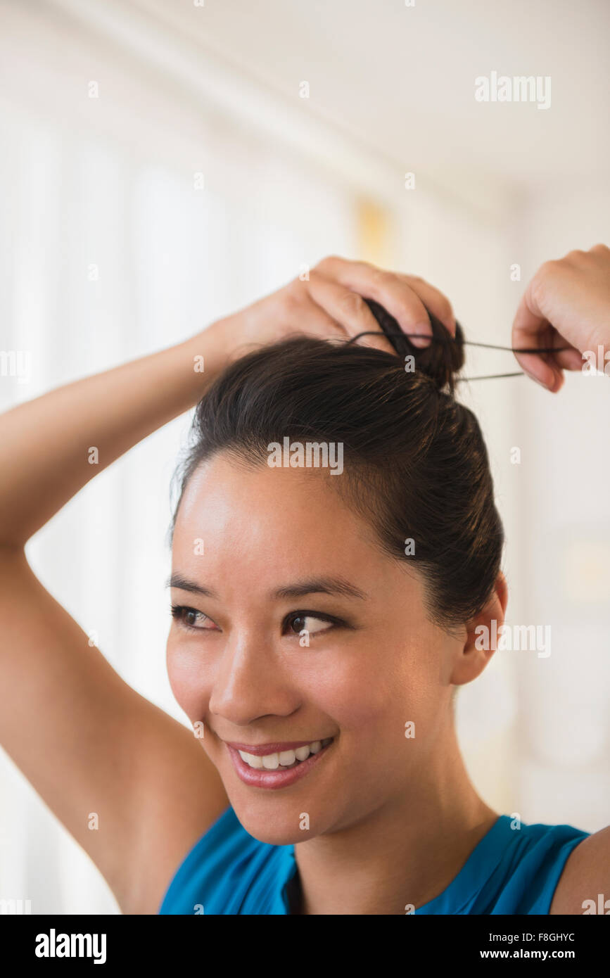 Donna cinese la legatura i suoi capelli di bun Foto Stock