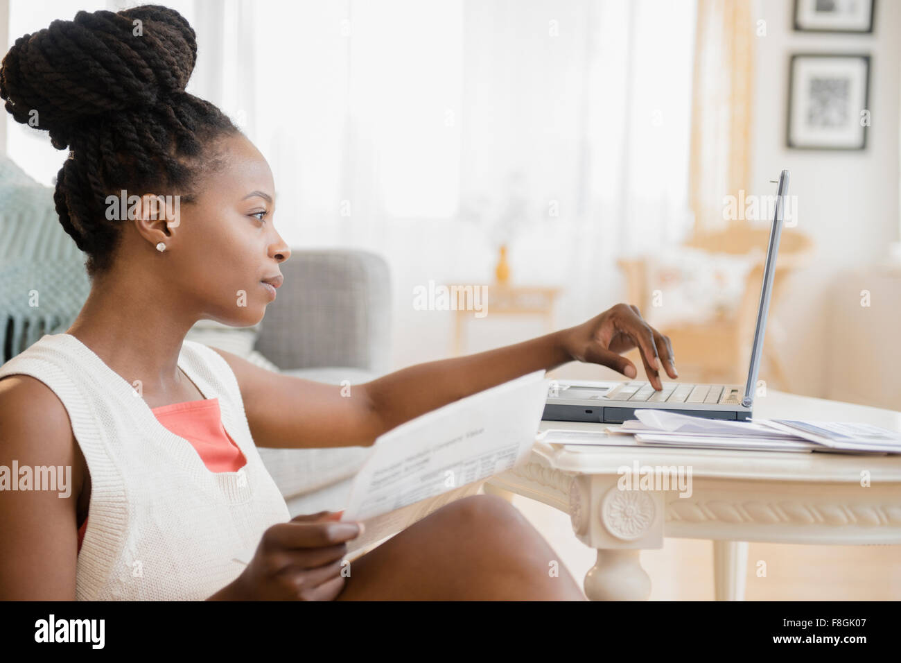 Nero donna il pagamento di fatture su laptop Foto Stock