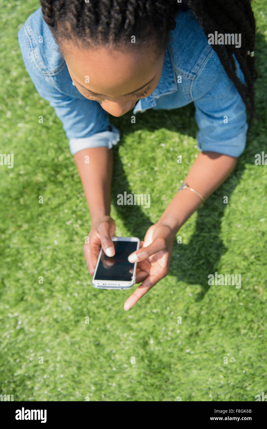Nero donna utilizzando il cellulare in erba Foto Stock