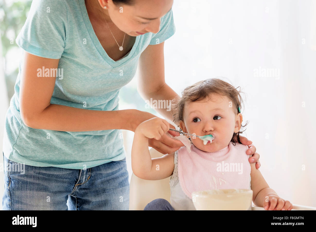 Alimentazione madre bimba in sedia alta Foto Stock