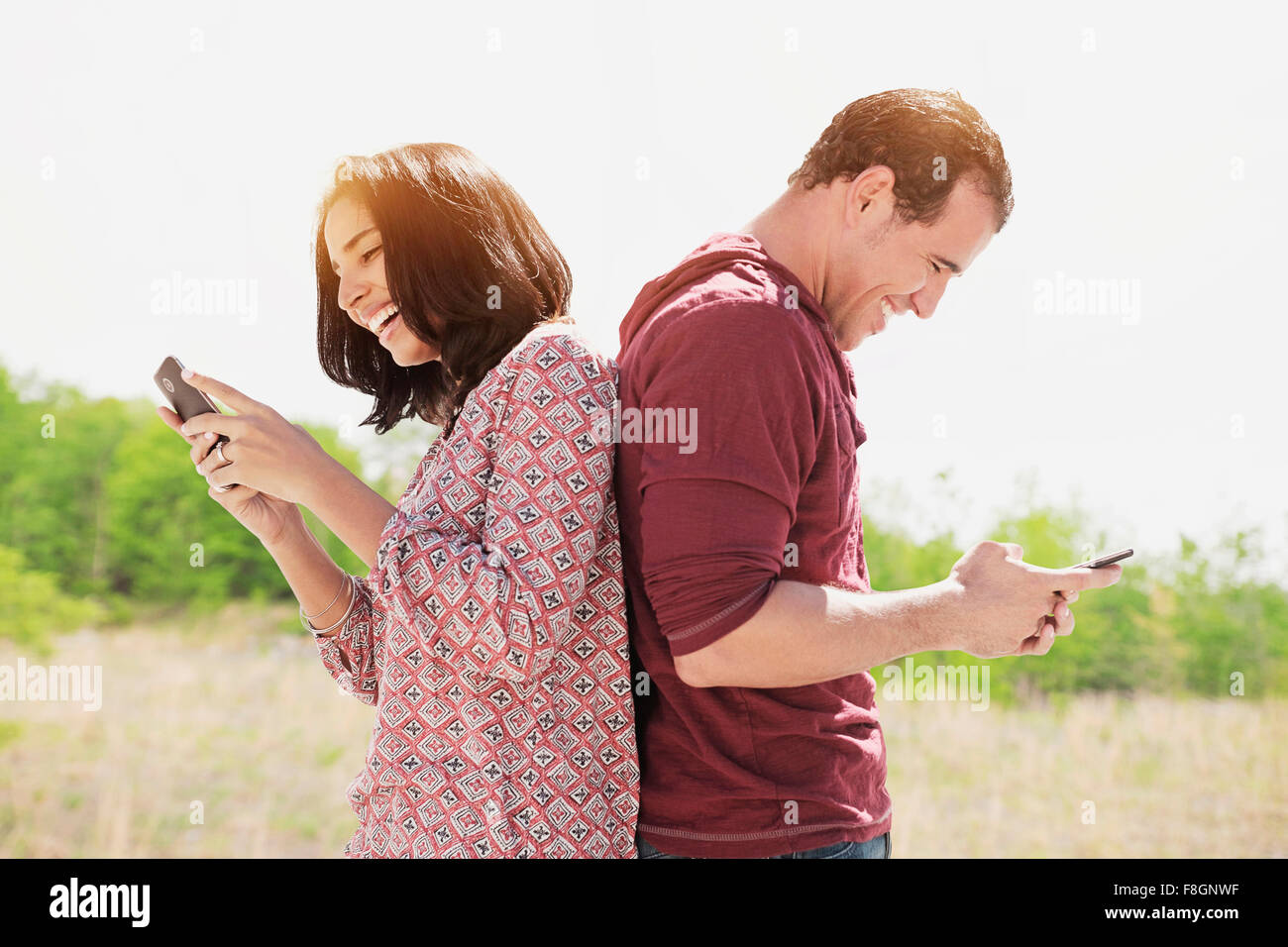 Coppia ispanica utilizzando i telefoni cellulari all'aperto Foto Stock