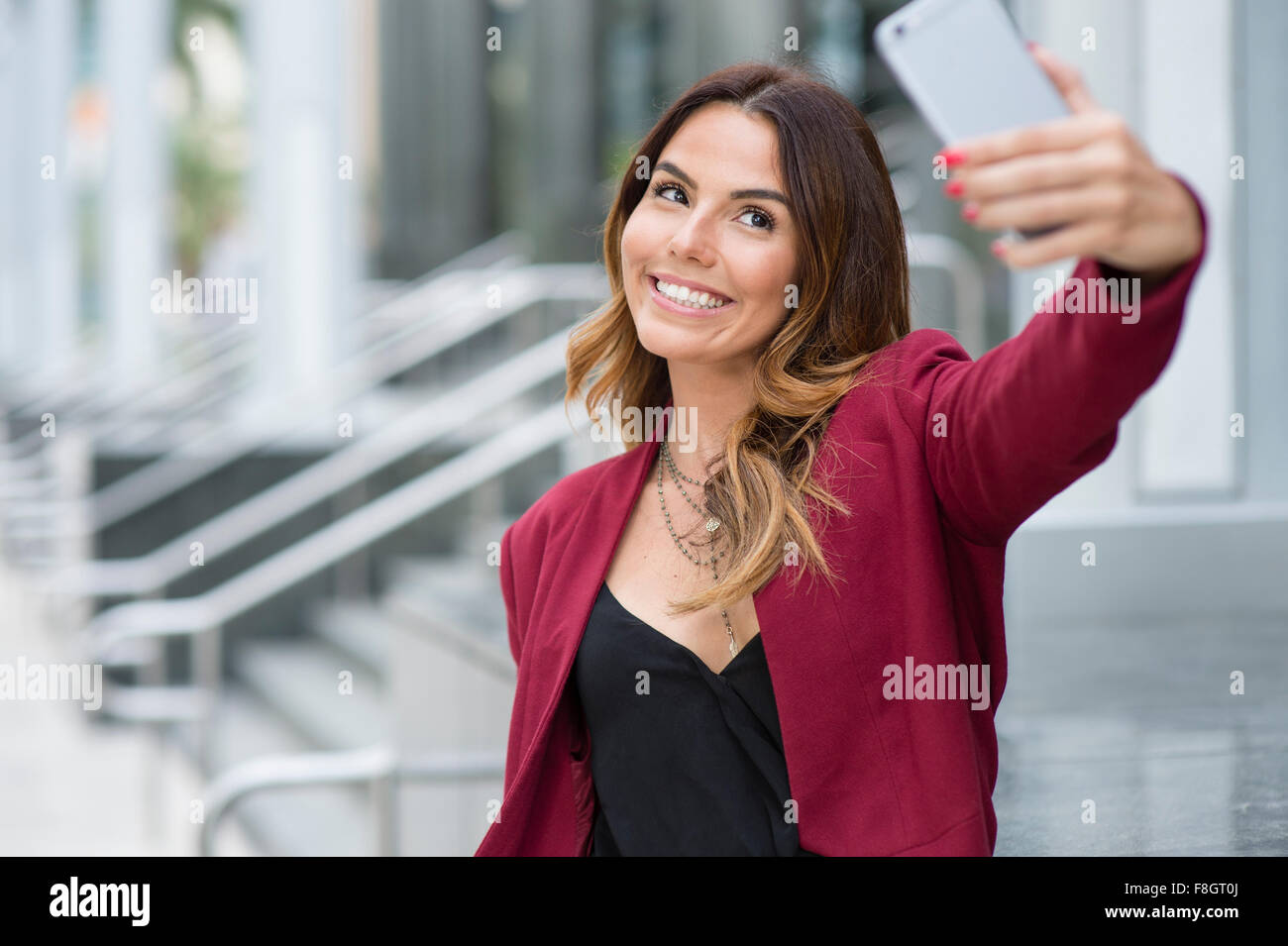 Imprenditrice ispanica tenendo selfie all'aperto Foto Stock