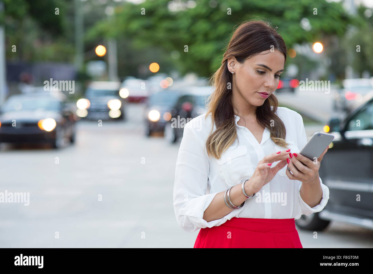 Imprenditrice ispanica tramite telefono cellulare all'aperto Foto Stock