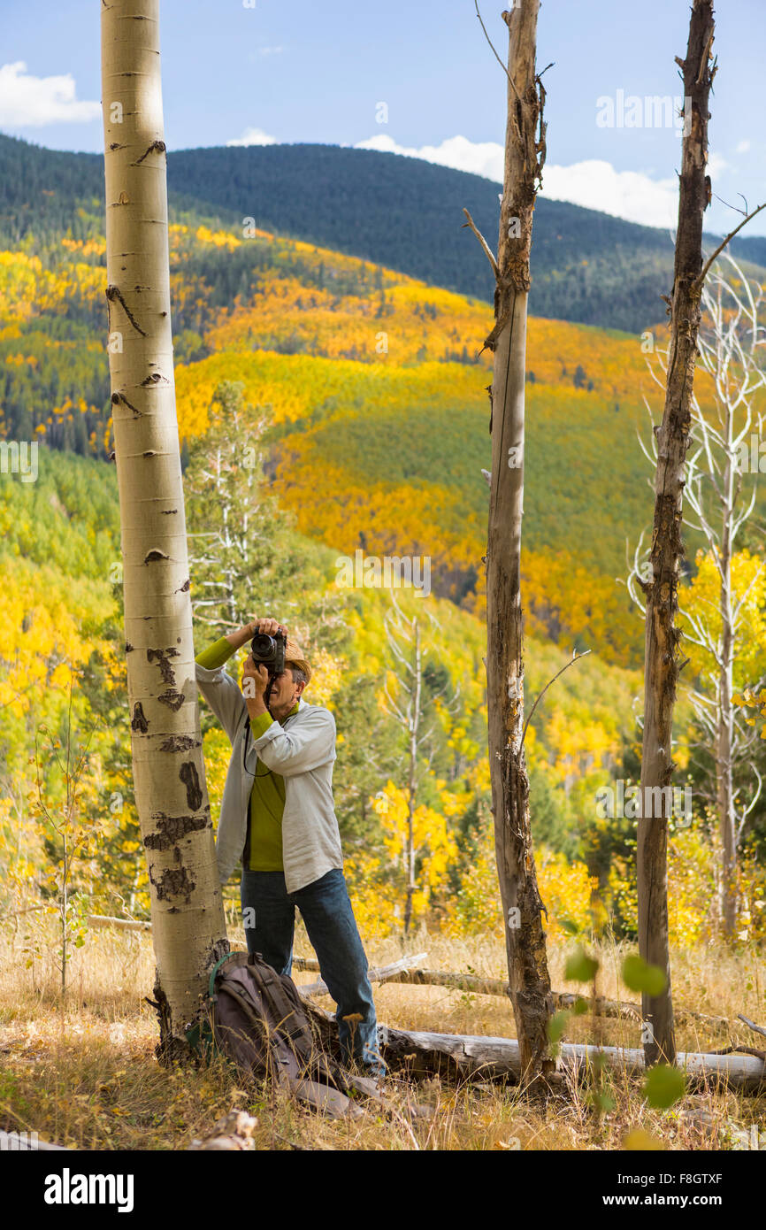 Uomo di fotografare con la fotocamera nella foresta di autunno Foto Stock