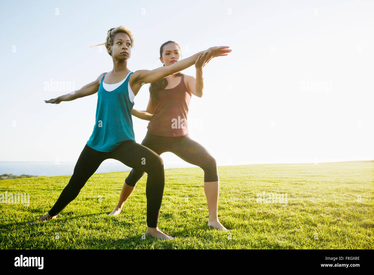 Docente aiutare lo studente pratica yoga all'aperto Foto Stock