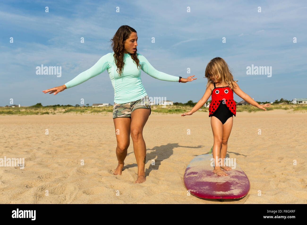 Madre figlia di insegnamento per il surf in spiaggia Foto Stock