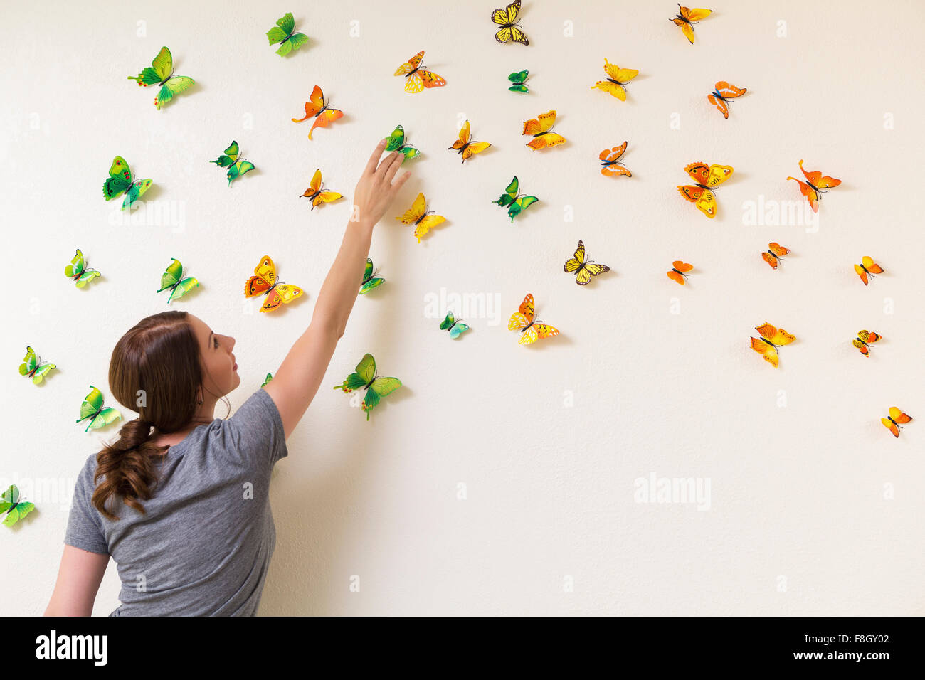 Razza mista donna parete decorazione con farfalle Foto Stock