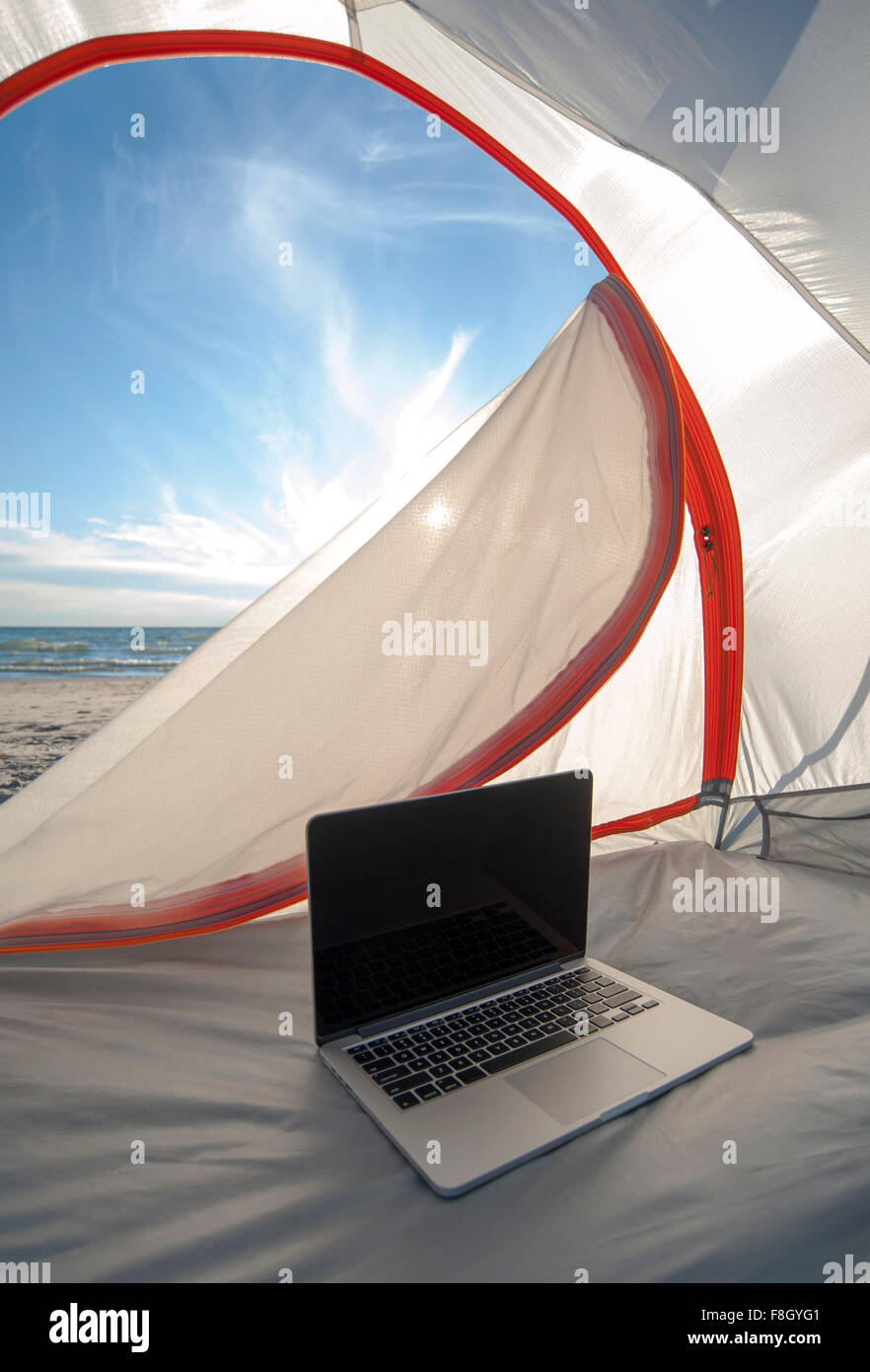 Laptop in tenda da campeggio sulla spiaggia Foto Stock