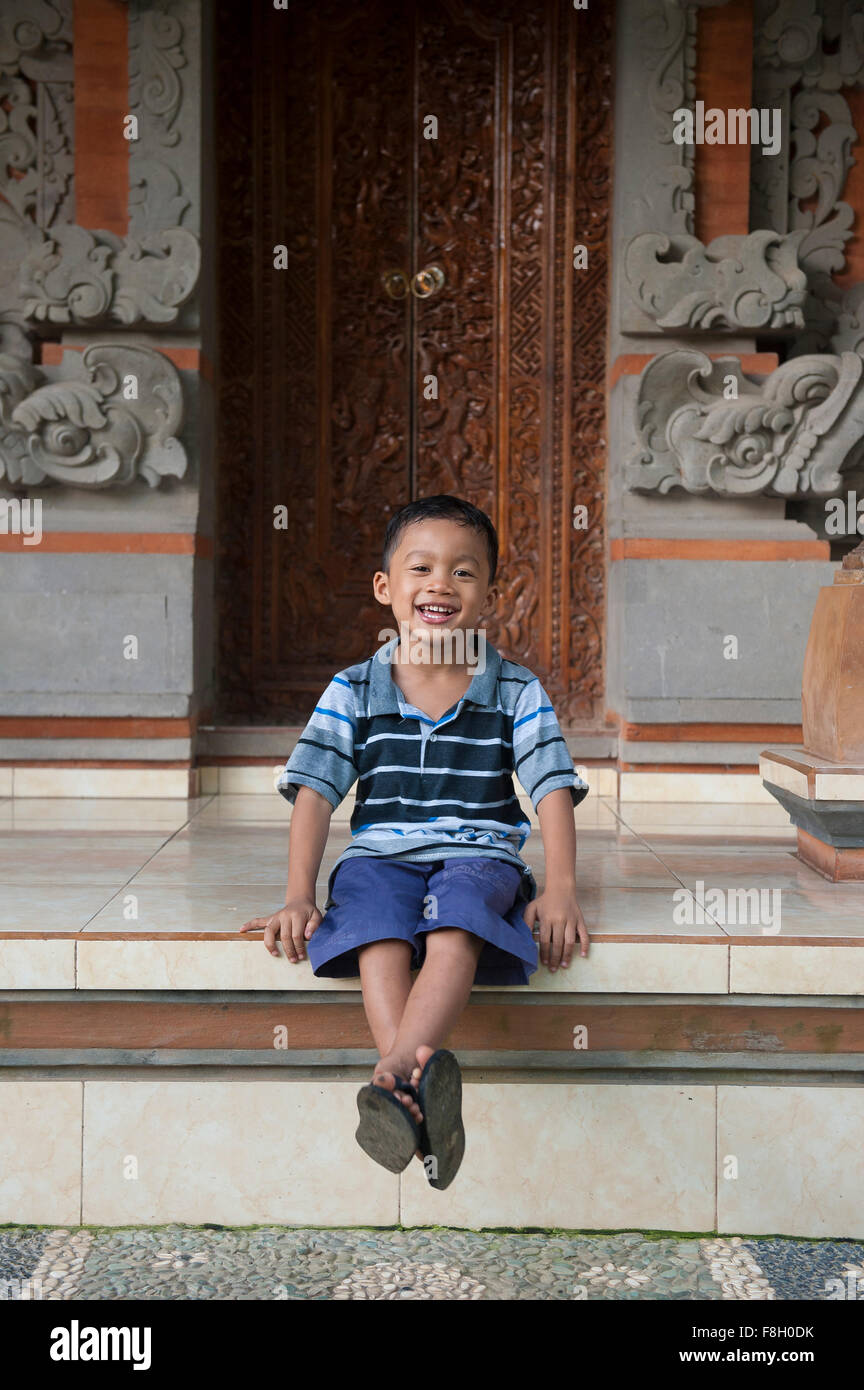 Asian ragazzo seduto fuori edificio ornato Foto Stock