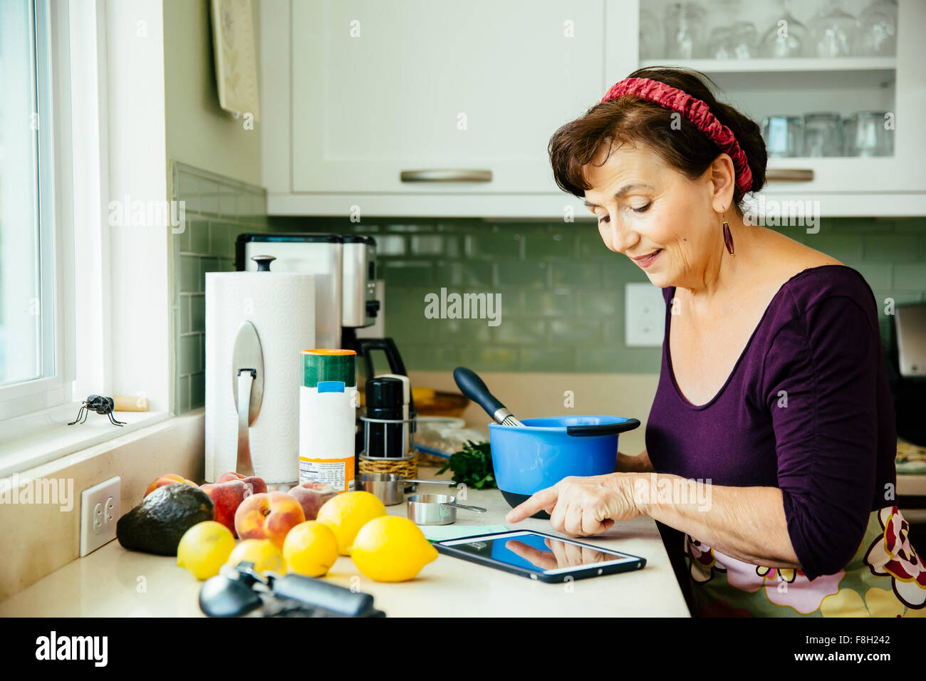 La donna caucasica utilizzando digitale compressa in cucina Foto Stock