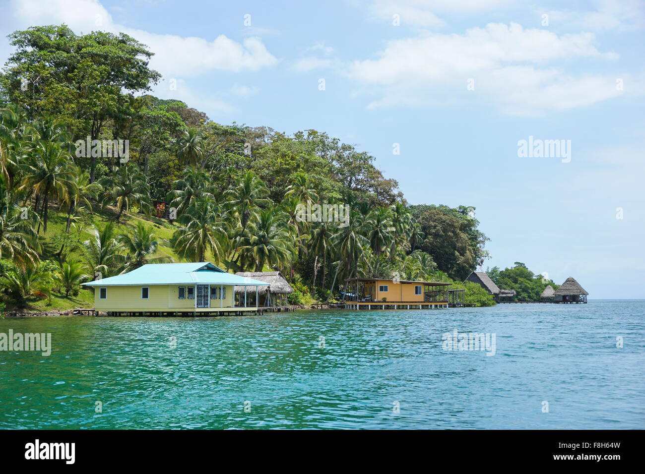 La vegetazione lussureggiante costa tropicale con case e capanne sull'acqua, viste dal mare dei Caraibi, Panama America Centrale Foto Stock