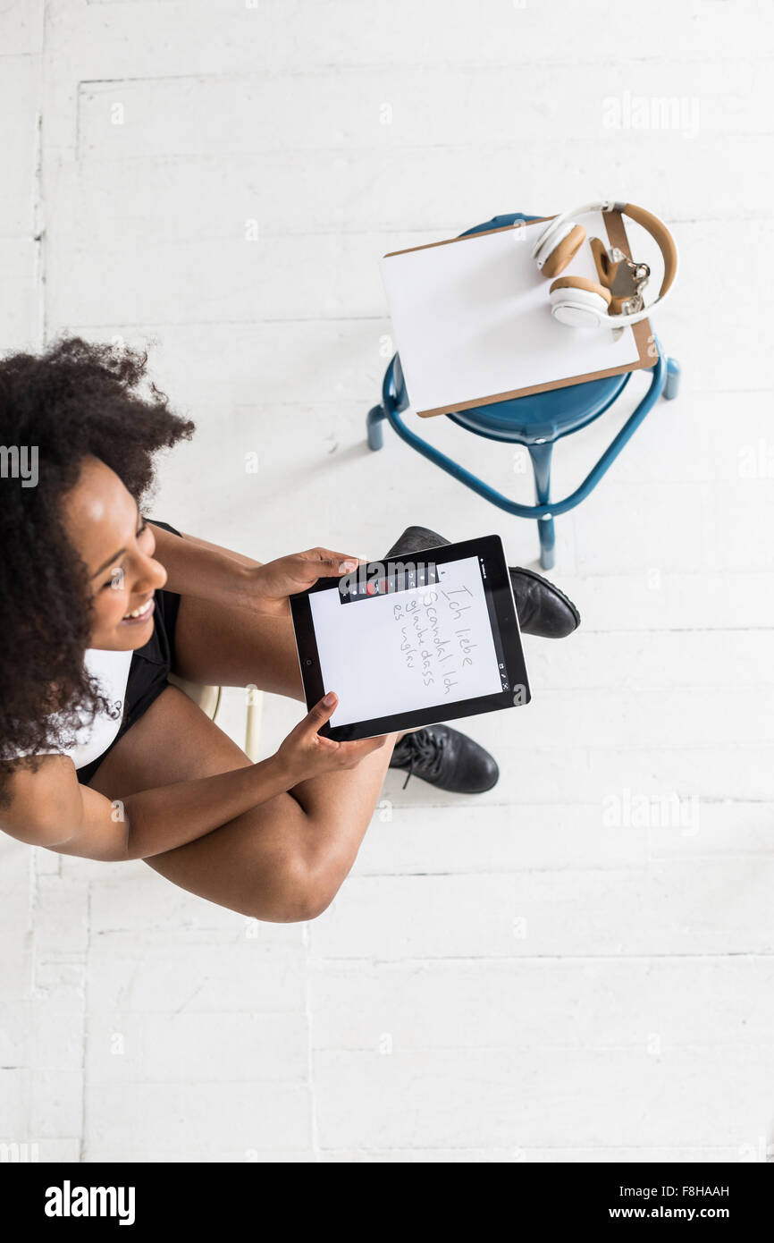 Una giovane donna Afroamericana utilizzando una compressa o un iPad in un tipo di studio impostazione Foto Stock