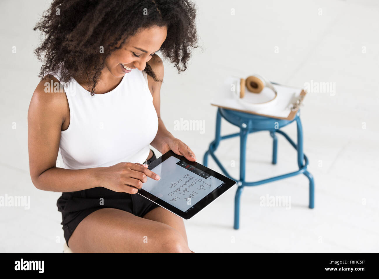 Una giovane donna Afroamericana utilizzando una compressa o un iPad in un tipo di studio impostazione Foto Stock