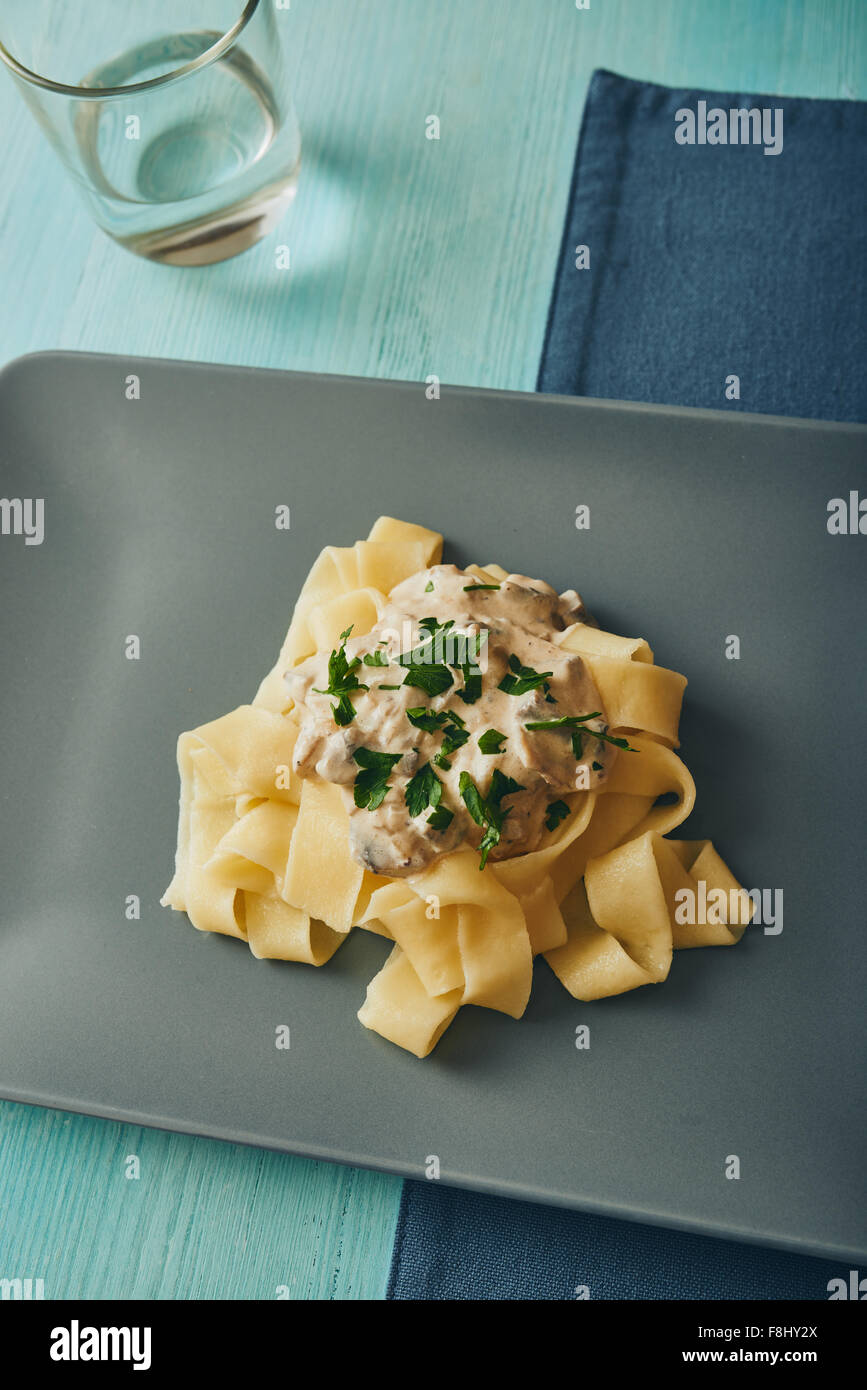 Pasta con funghi e crema su grigio piatto quadrato Foto Stock