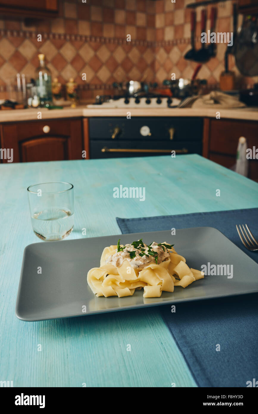 Pasta con funghi e crema su grigio piatto quadrato Foto Stock
