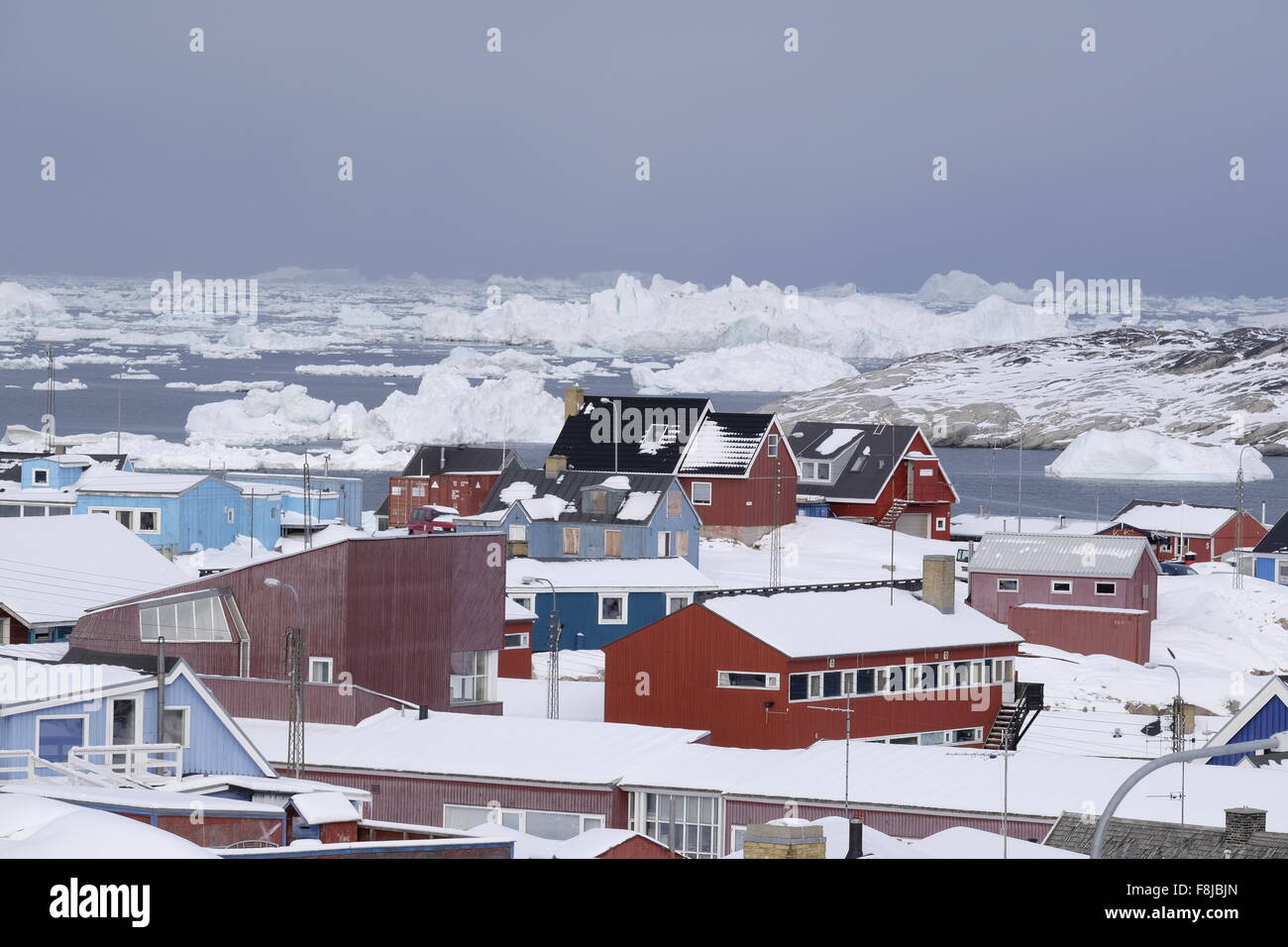 Ilulissat colorate case di città dietro iceberg galleggianti a Disko Bay, Groenlandia Foto Stock