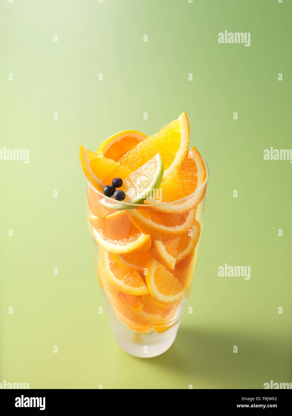 Gli ingredienti nel bicchiere per orange, calce e il ginepro di succo di frutti di bosco Foto Stock