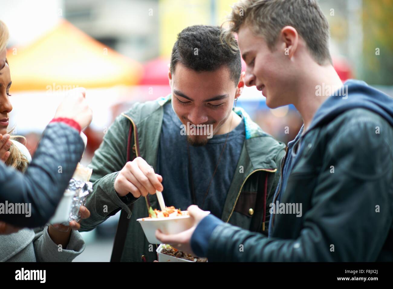 Un gruppo di giovani adulti di mangiare cibo da asporto, all'aperto Foto Stock