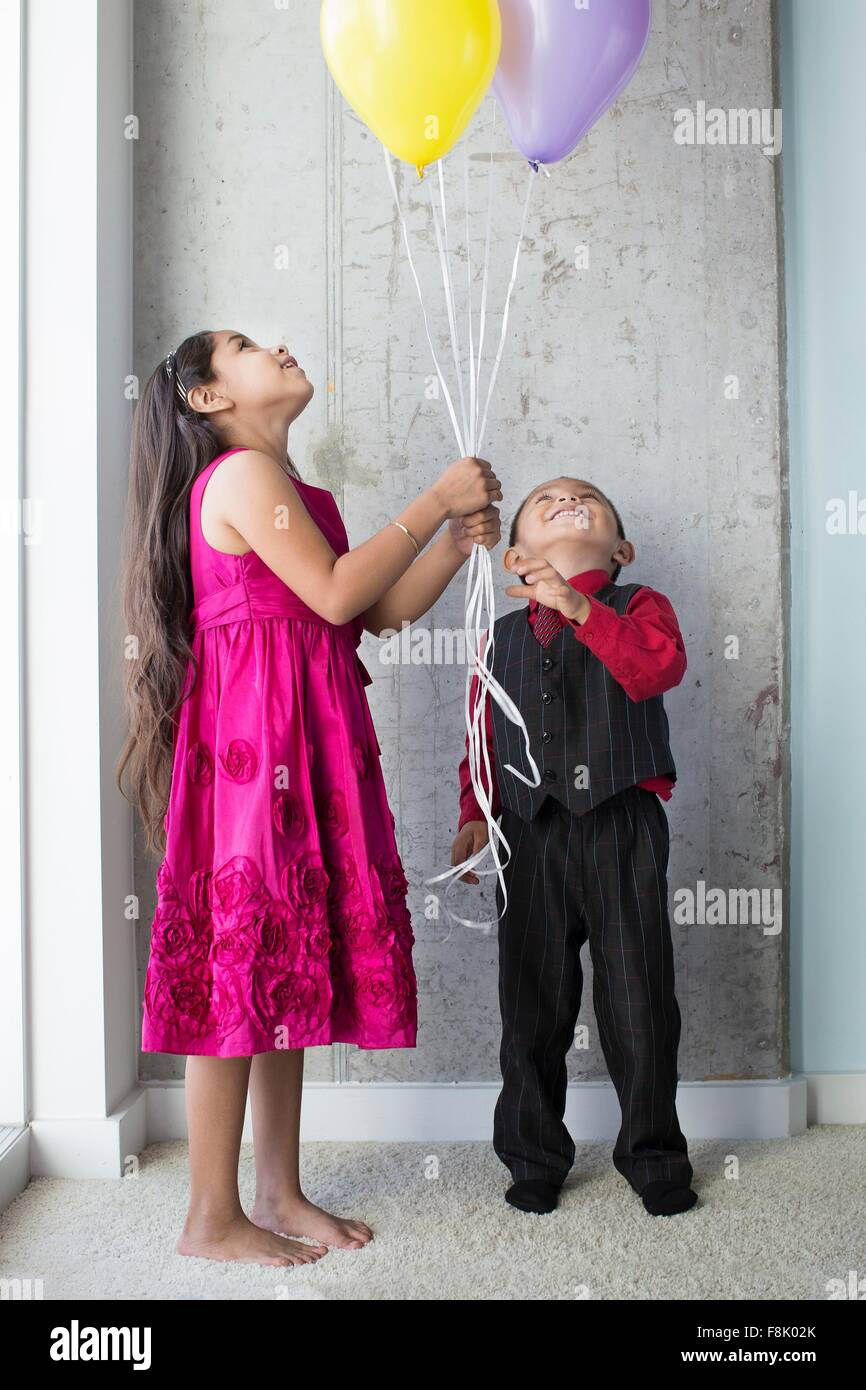 Giovane ragazza e ragazzo, tenendo palloncini Foto Stock