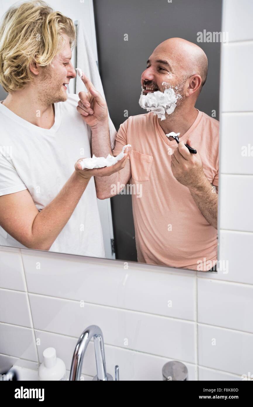 Specchio bagno immagine della coppia maschio ingannare intorno mentre la rasatura Foto Stock