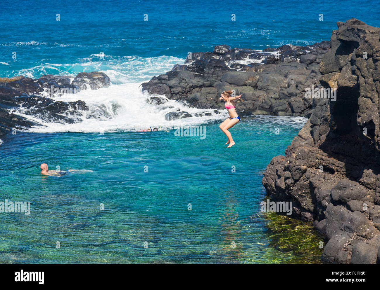 Donna salta in piscina calma del Queens bagno piscina marea sulla costa vicino a Princeville, Kauai, Hawaii Foto Stock