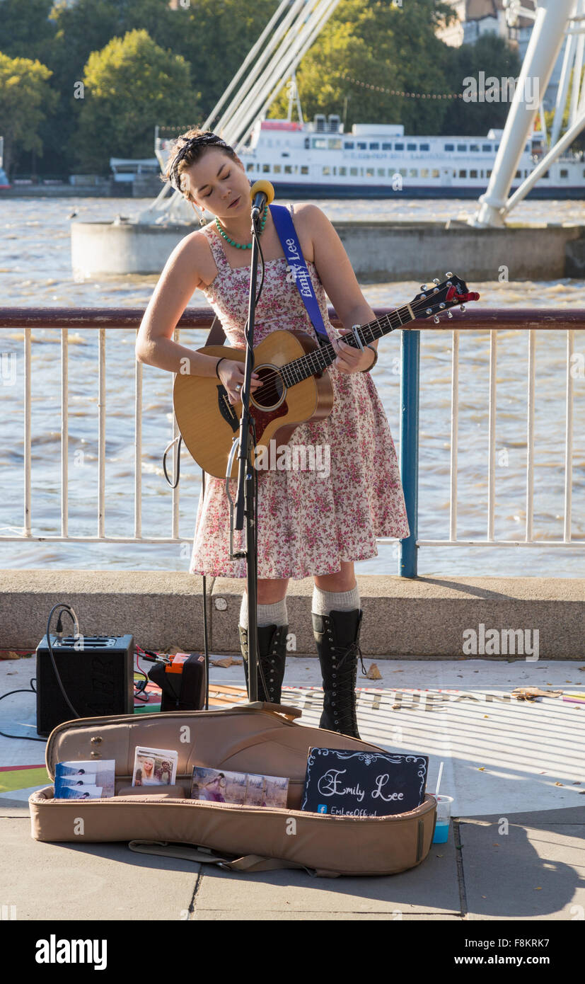 Busker con la chitarra dal lato del fiume Tamigi a Londra in Inghilterra Foto Stock
