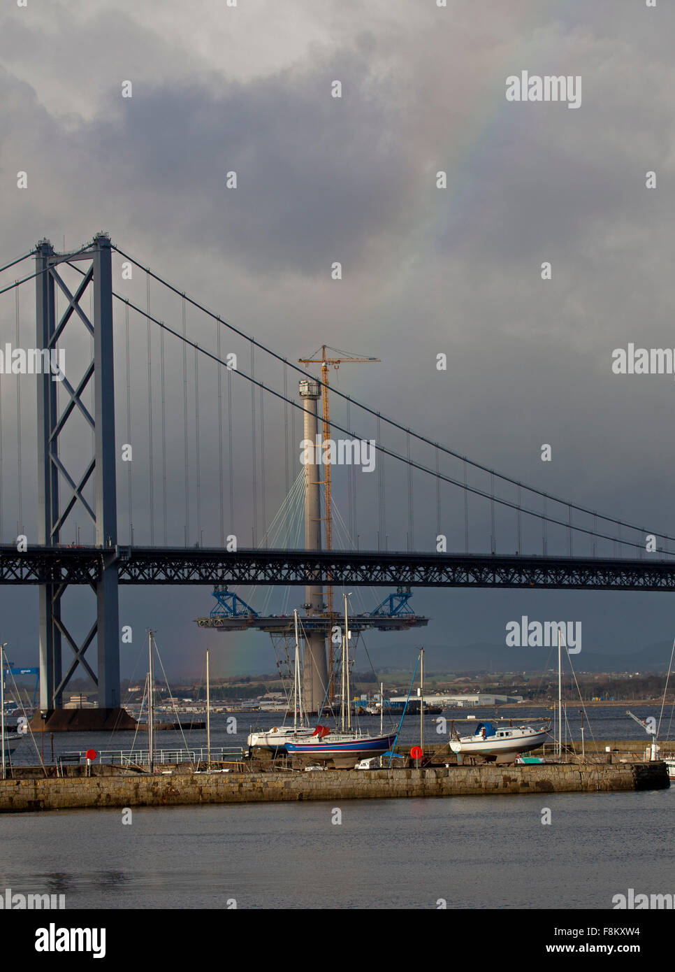 Forth Road Bridge, Queensferry, Edimburgo. 10 dicembre, 2015. Un arcobaleno appare dietro il Forth Road Bridge forse con la promessa di una riparazione rapida. Lavorando intorno all'orologio di un team di ingegneri di Amey hanno presentato un piano per fissare la crepa su uno del ponte di travatura reticolare di maglie di estremità. Vento prevalente velocità vengono continuamente valutati per garantire la sicurezza dei lavoratori e del personale. Il programma di riparazione è in programma per il completamento del nuovo anno. Foto Stock