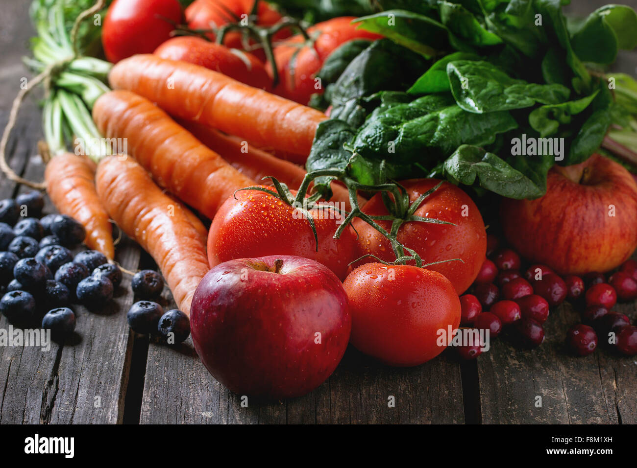 Assortimento di frutta fresca, verdura e bacche di carote, spinaci, i pomodori, le mele rosse, mirtilli e mirtilli rossi sopra il vecchio w Foto Stock Assortimento di frutta fresca, verdura e bacche di carote, spinaci, i pomodori, le mele rosse, mirtilli e mirtilli rossi sopra il vecchio w Foto Stock