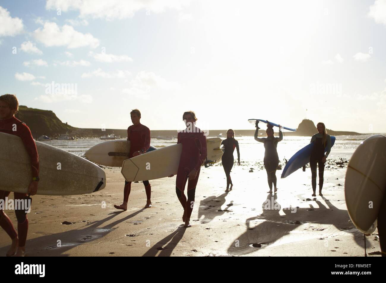 Gruppo di surfers, passeggiate sulla spiaggia, portando le tavole da surf Foto Stock