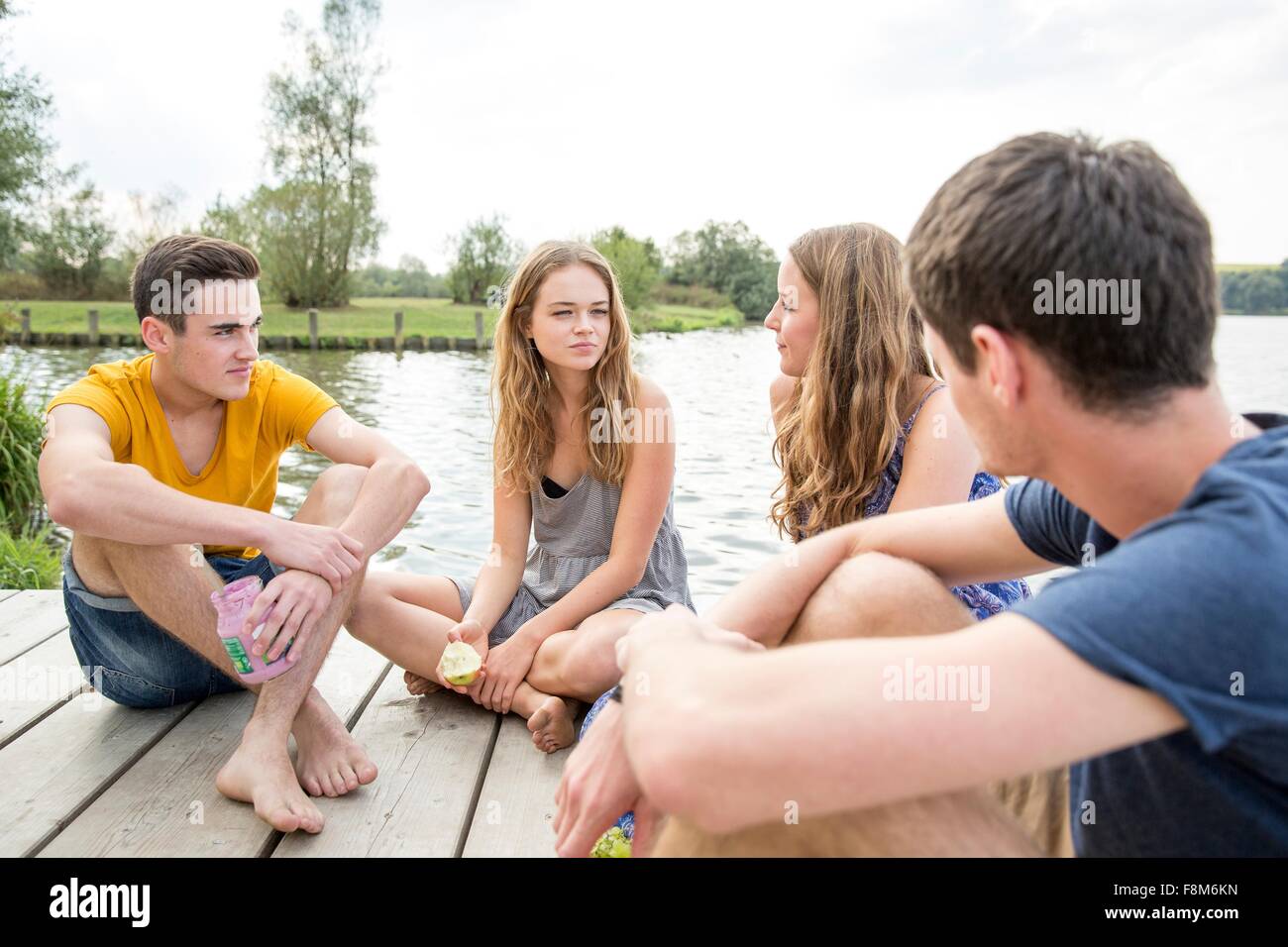 Un gruppo di giovani adulti seduti sul molo, rilassante Foto Stock