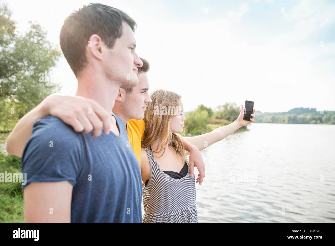 Tre giovani adulti tenendo autoritratto, utilizza lo smartphone, all'aperto Foto Stock