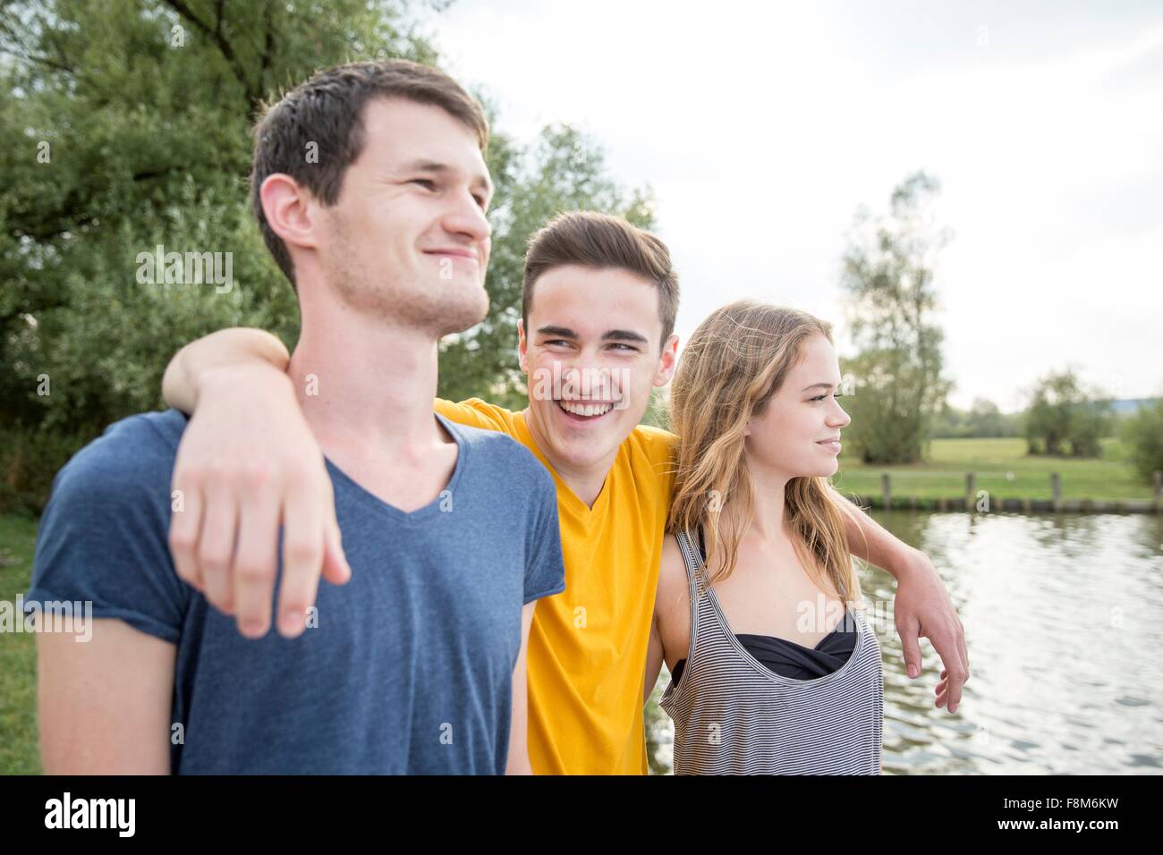 Un gruppo di giovani adulti, in piedi dal lago, sorridente Foto Stock
