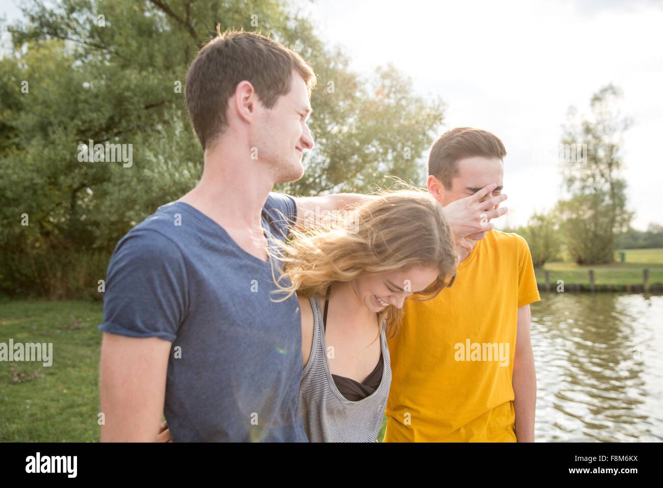 Un gruppo di giovani adulti, in piedi dal lago, ingannare intorno, ridendo Foto Stock