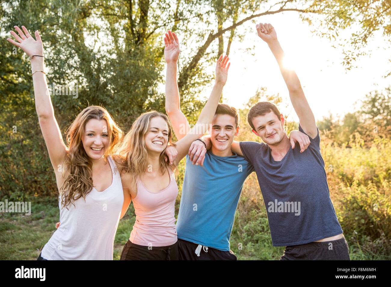 Ritratto di gruppo di amici in ambiente rurale, bracci sollevati, sorridente Foto Stock