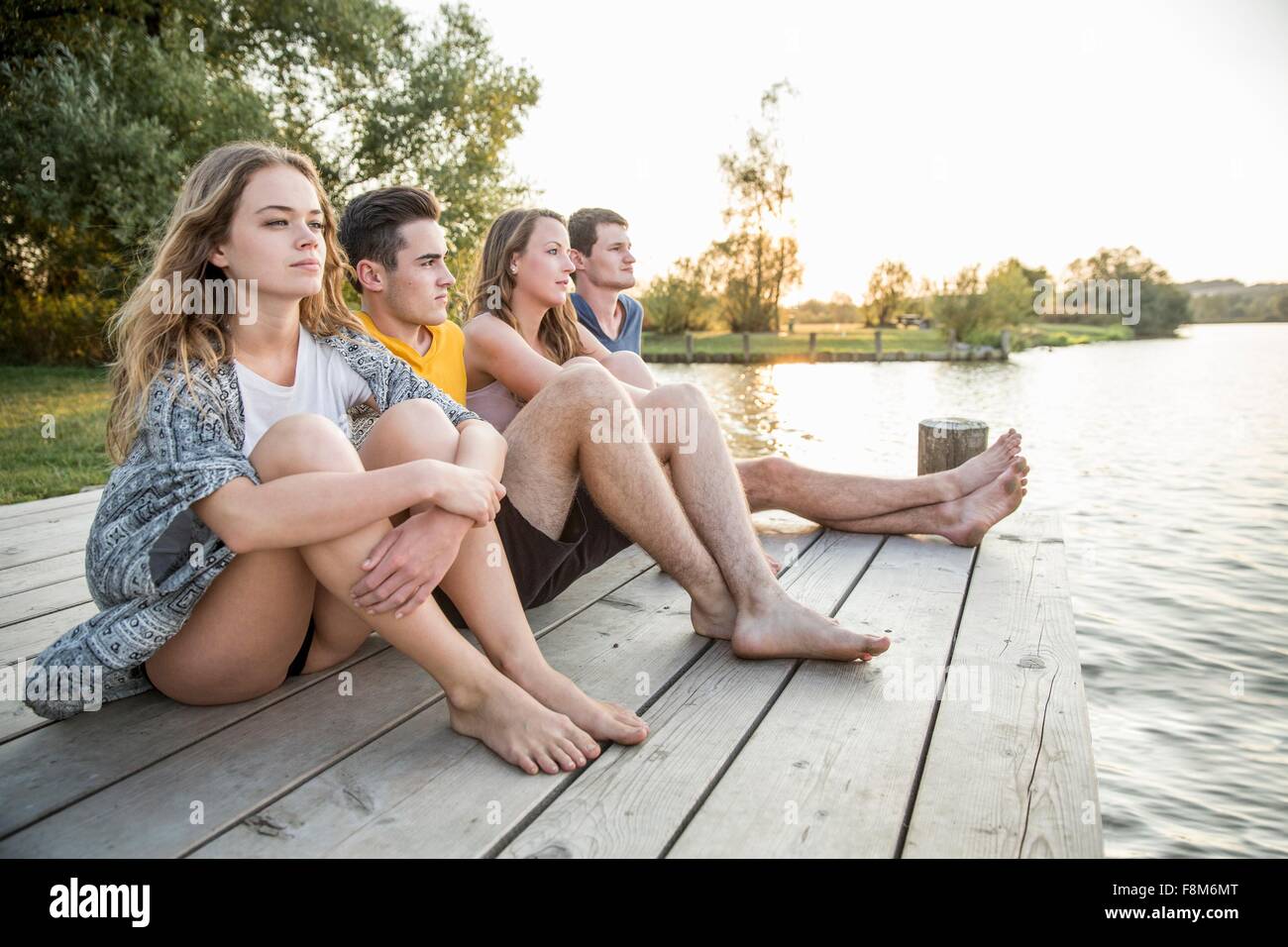 Gruppo di amici seduti sul molo, rilassante Foto Stock