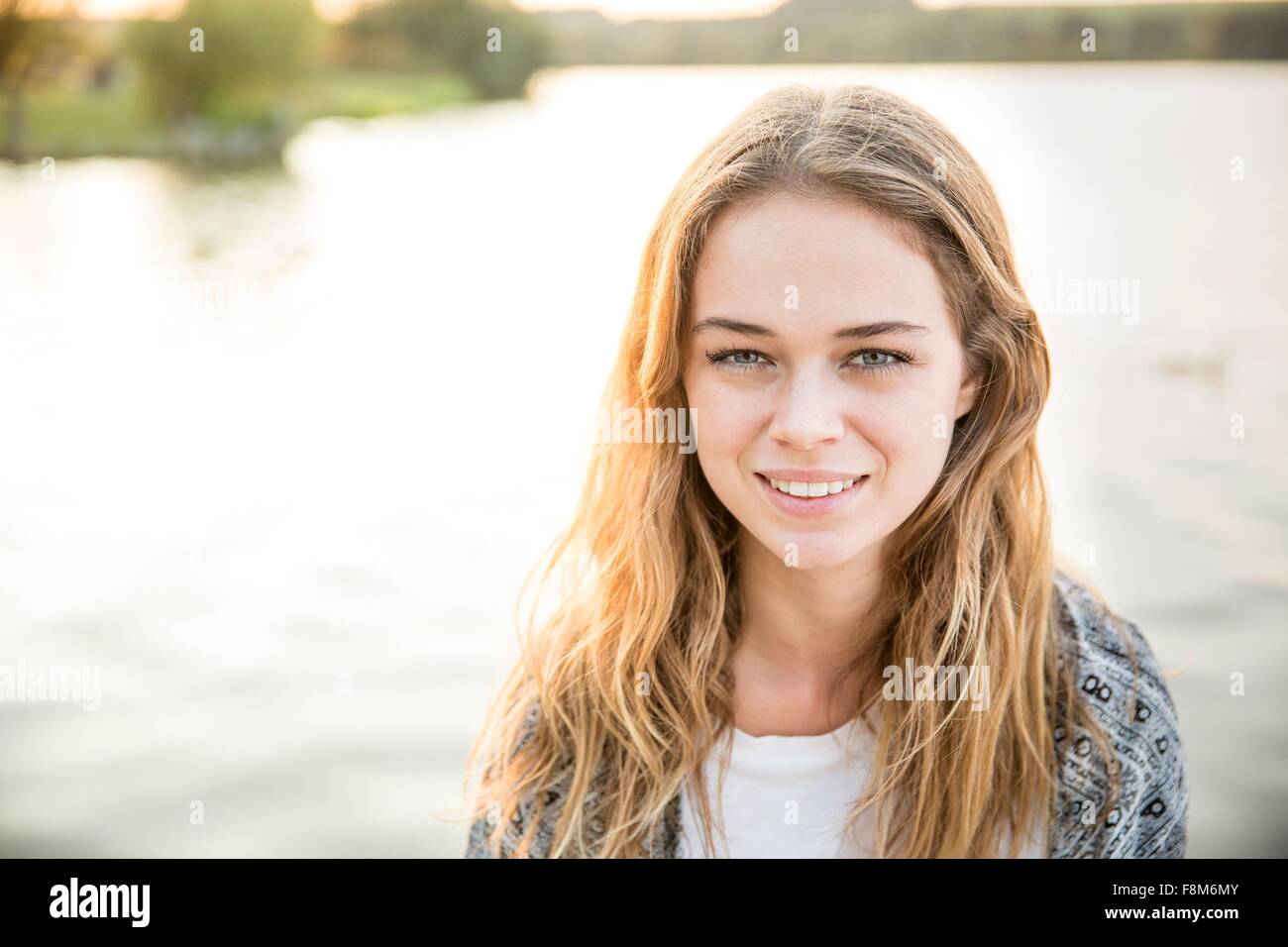 Ritratto di giovane donna accanto al lago, sorridente Foto Stock