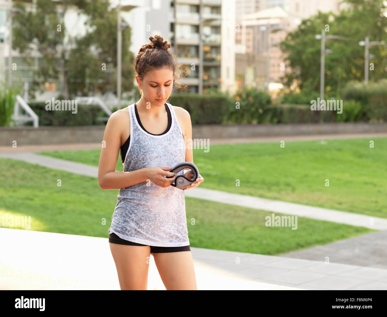 Giovane donna di contenimento del peso del polso in posizione di parcheggio Foto Stock