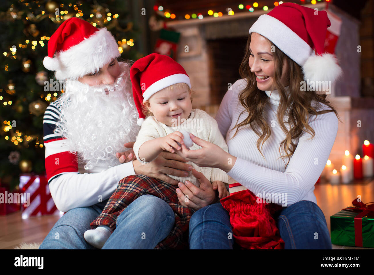 La famiglia felice avente un divertimento vicino a albero di Natale e caminetto in soggiorno Foto Stock