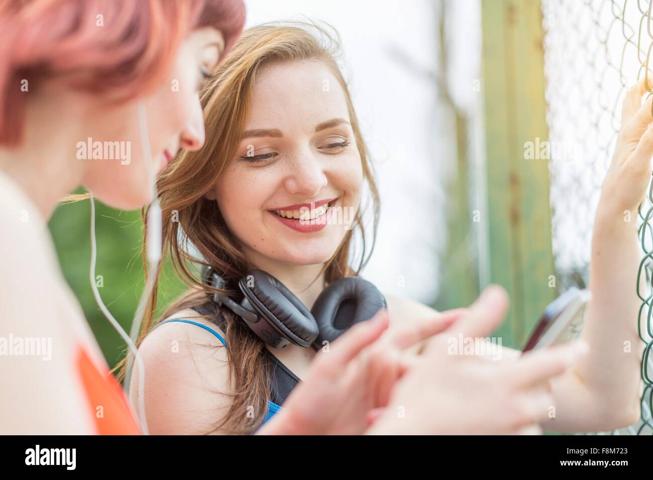 Giovani donne utilizza lo smartphone a fianco di recinzione Foto Stock