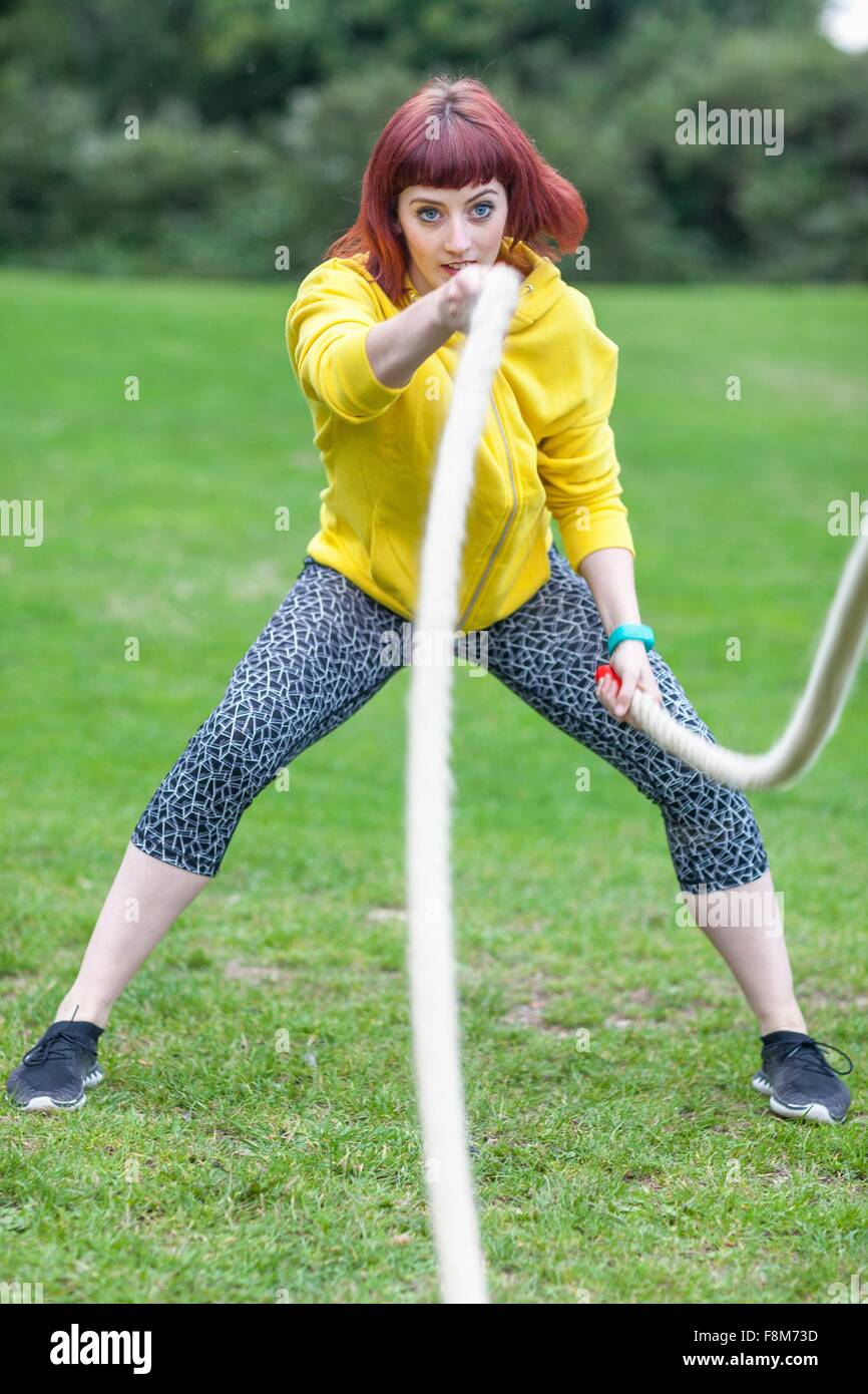 Giovane donna tirando la corda sul campo Foto Stock