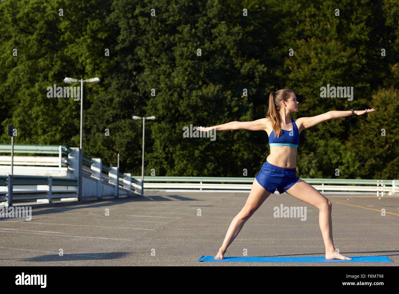 Giovane donna a praticare yoga in ambiente urbano parcheggio Foto Stock