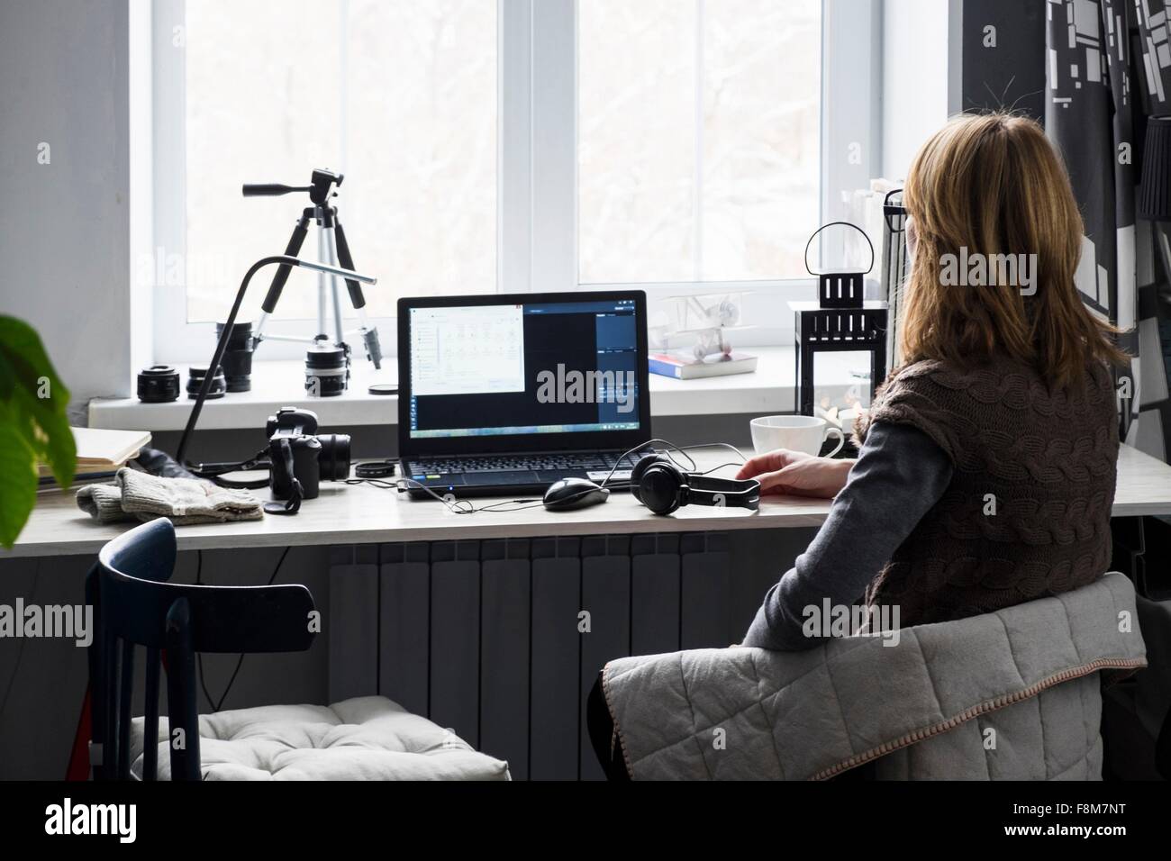 Metà donna adulta seduto alla scrivania, utilizzando il computer, vista posteriore Foto Stock