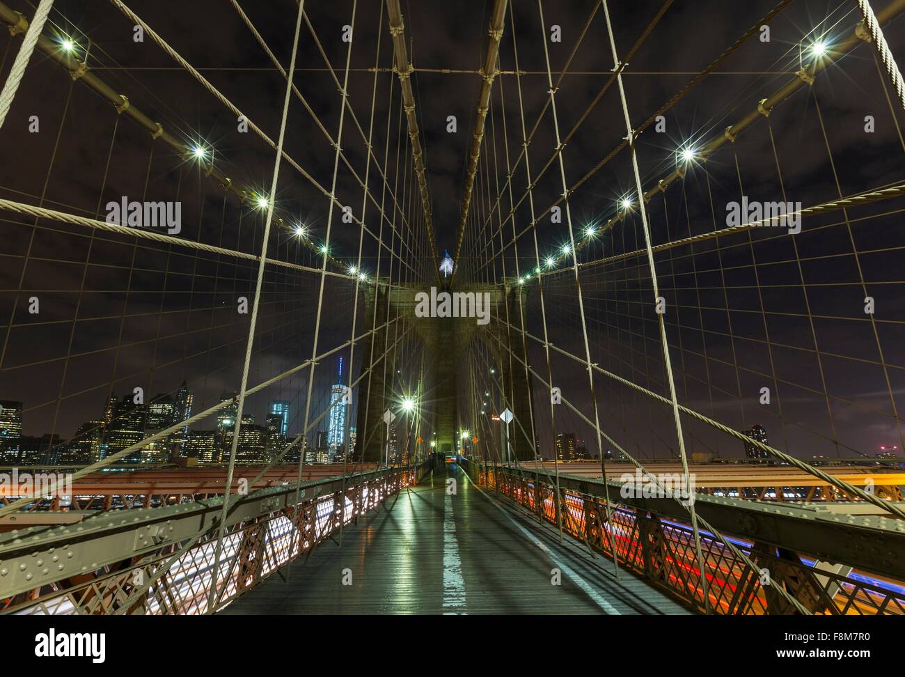Ponte di Brooklyn marciapiede e distante Manhattan financial district skyline notturno, New York, Stati Uniti d'America Foto Stock