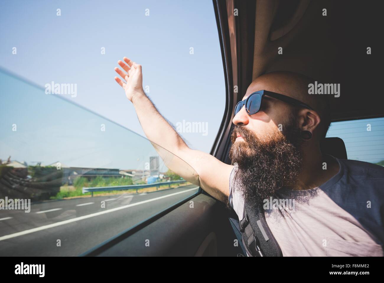 Barbuto man mano bloccata al di fuori della finestra di auto su autostrada, Garda, Italia Foto Stock