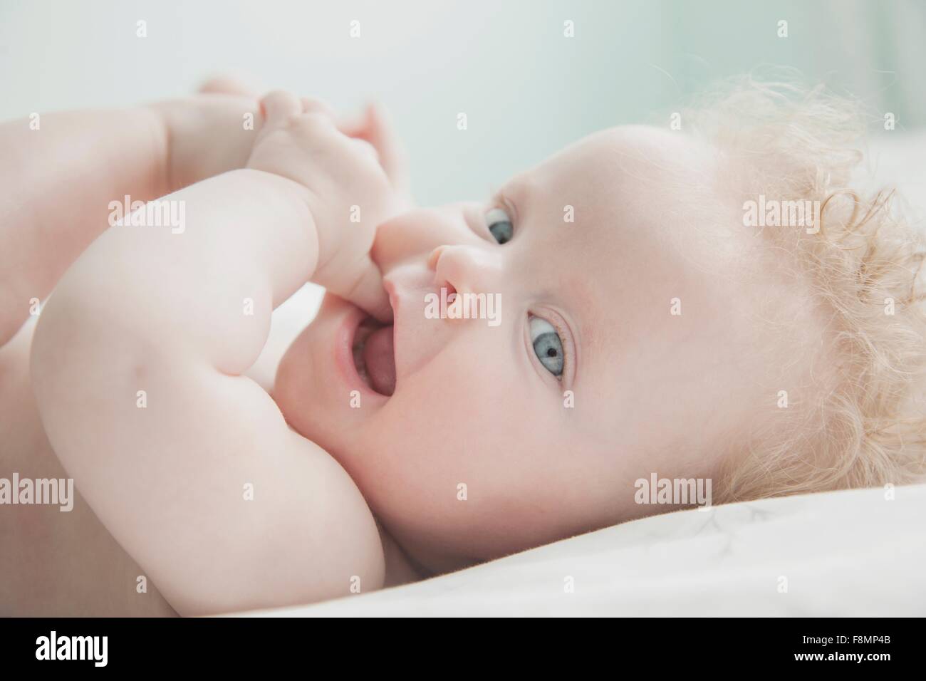 Baby girl sdraiato, le dita in bocca Foto Stock