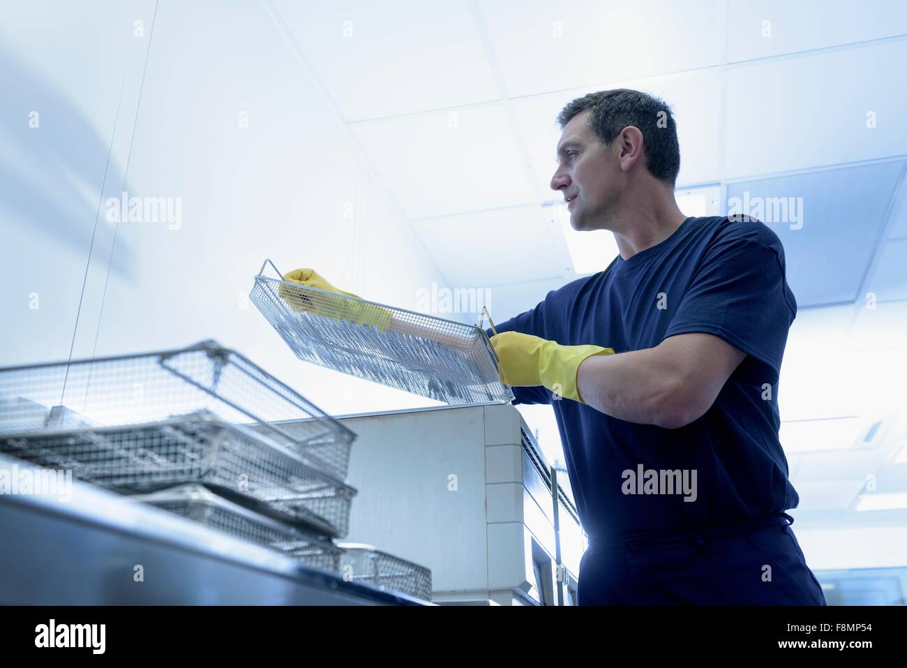 Lavoratore di mettere gli strumenti chirurgici in bagno ad ultrasuoni in strumento chirurgico factory Foto Stock