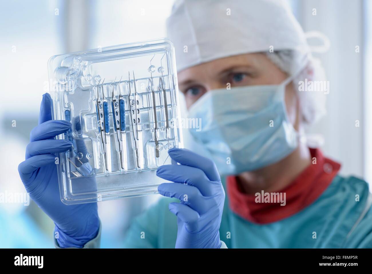 Lavoratore di ispezionare gli strumenti chirurgici in clean room di strumenti chirurgici fabbrica, close up Foto Stock