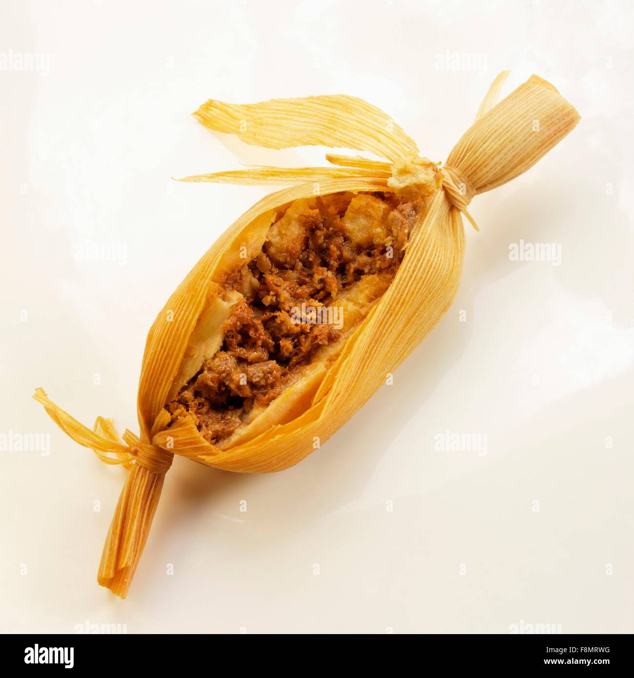 Uno di carne riempito Tamale tagliata aperta; sullo sfondo bianco Foto Stock